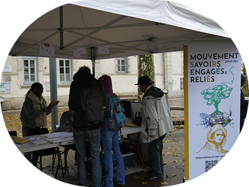 Photo de trois personnes devant un stand avec un kakemono 