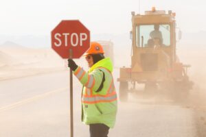 Un ouvrier de travaux publics tient un panneau "stop"