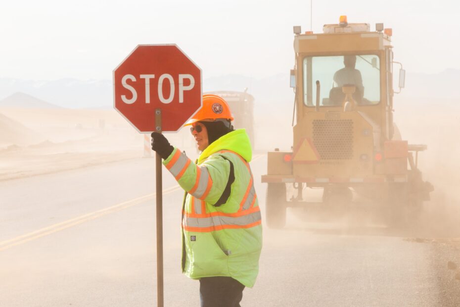 Un ouvrier de travaux publics tient un panneau "stop"